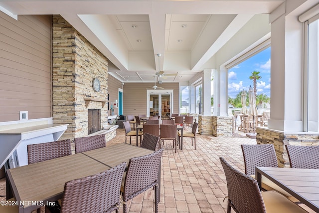 dining space with wooden walls, ceiling fan, and a stone fireplace