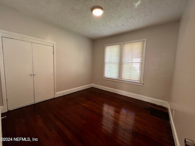 unfurnished bedroom with a closet, dark hardwood / wood-style flooring, and a textured ceiling