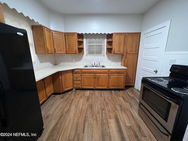 kitchen with black appliances, sink, decorative backsplash, and hardwood / wood-style flooring