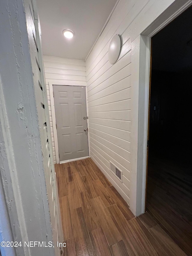 corridor with hardwood / wood-style floors and wood walls