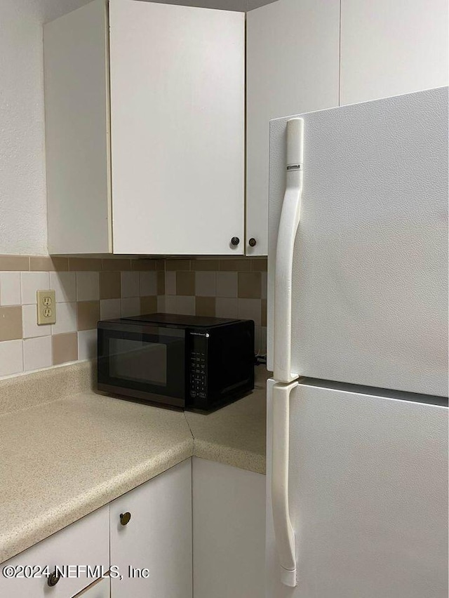 kitchen with decorative backsplash, white cabinets, and white fridge