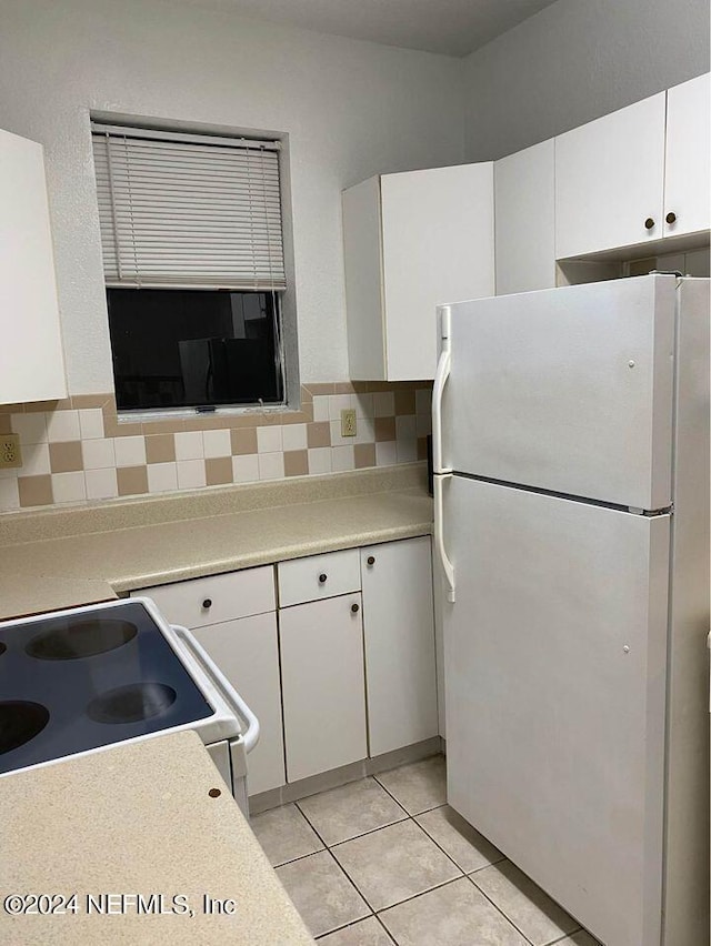 kitchen with white cabinets, white appliances, light tile patterned floors, and backsplash