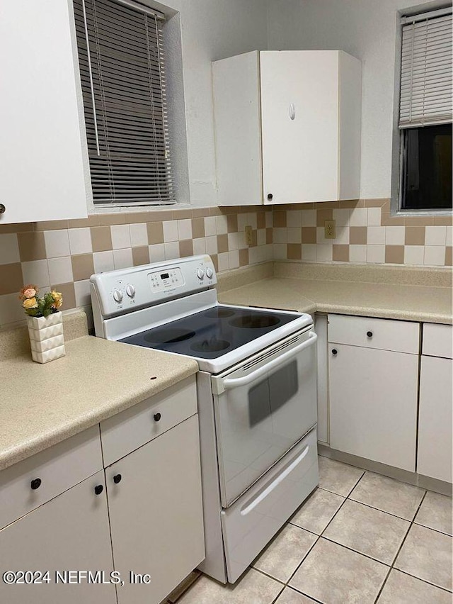 kitchen featuring white electric stove, decorative backsplash, and white cabinets