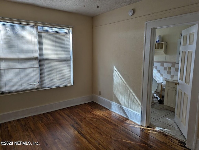 empty room with dark wood-type flooring and a textured ceiling