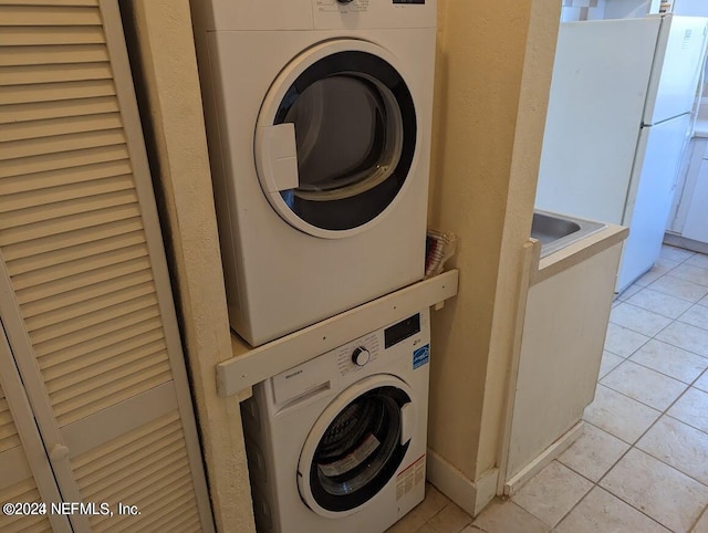 laundry room featuring light tile patterned floors and stacked washer / drying machine