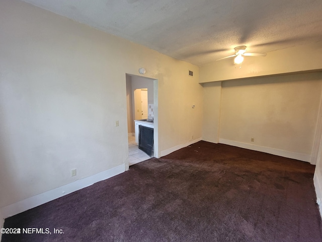 carpeted empty room featuring ceiling fan and a textured ceiling