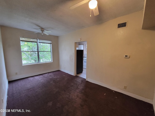 carpeted empty room featuring ceiling fan and a textured ceiling