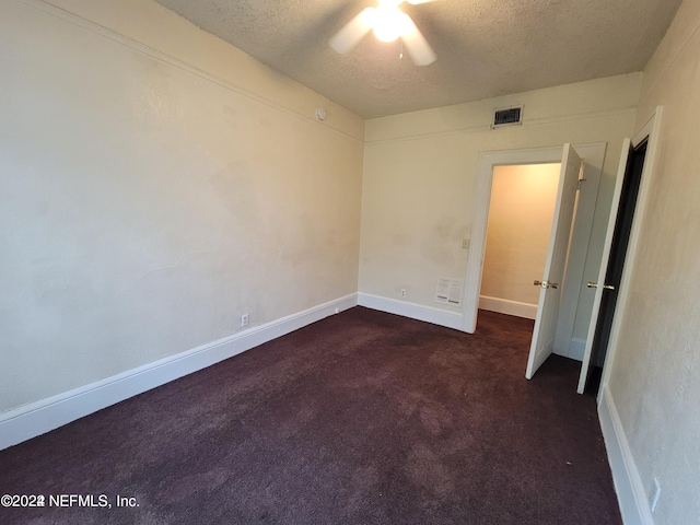 unfurnished bedroom featuring ceiling fan, dark colored carpet, and a textured ceiling