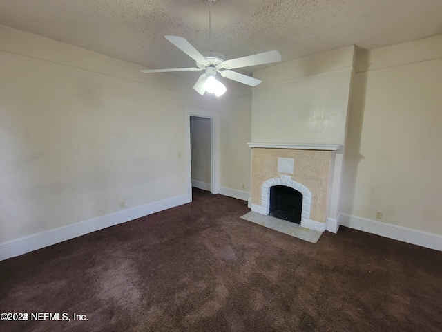 unfurnished living room with ceiling fan, dark colored carpet, a textured ceiling, and a brick fireplace