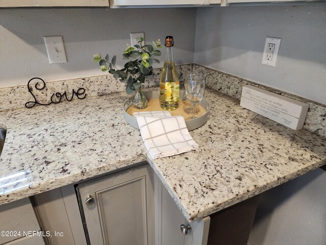 room details featuring gray cabinetry and light stone counters