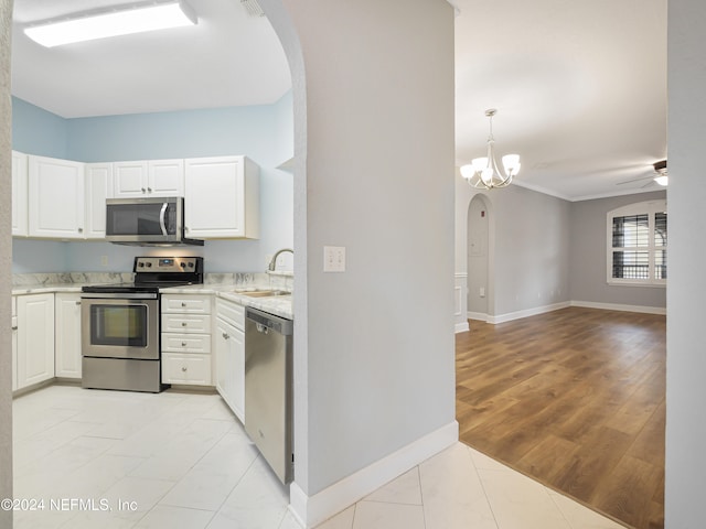 kitchen with ceiling fan with notable chandelier, light hardwood / wood-style flooring, appliances with stainless steel finishes, sink, and white cabinets