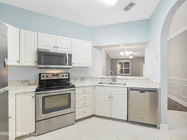 kitchen featuring white cabinets, stainless steel appliances, a notable chandelier, and sink