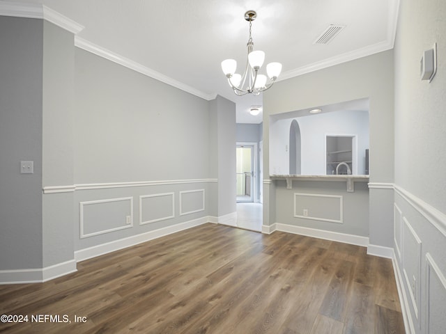 empty room with dark hardwood / wood-style floors, a chandelier, and crown molding