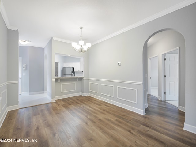 empty room featuring crown molding, dark hardwood / wood-style floors, and an inviting chandelier