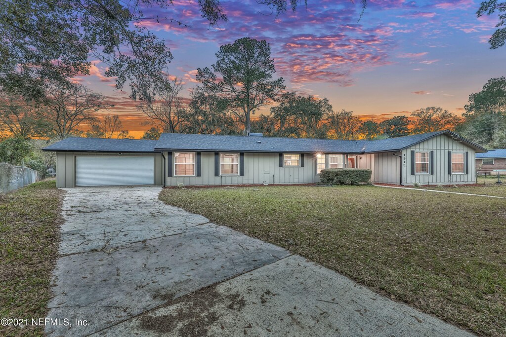 ranch-style house with a garage and a lawn