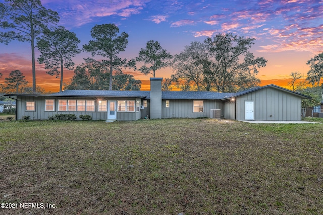 ranch-style home with a yard and central AC unit