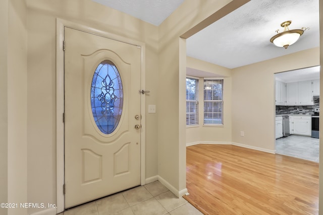 foyer entrance featuring a textured ceiling and light hardwood / wood-style flooring