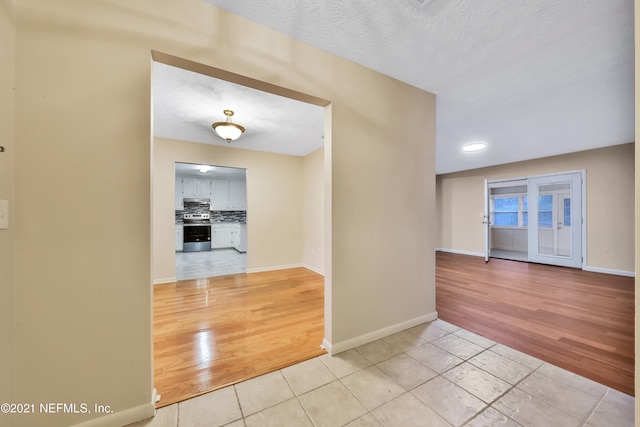 hall featuring a textured ceiling and light hardwood / wood-style floors