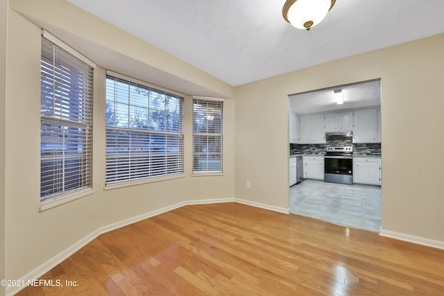 unfurnished living room with a textured ceiling and light hardwood / wood-style flooring