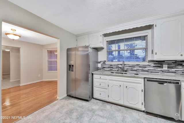 kitchen featuring light hardwood / wood-style flooring, stainless steel appliances, sink, decorative backsplash, and white cabinets