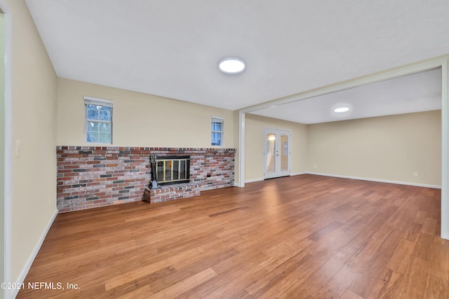 unfurnished living room with hardwood / wood-style flooring, a brick fireplace, and brick wall