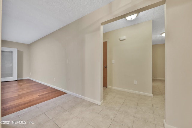 empty room with a textured ceiling and light hardwood / wood-style floors