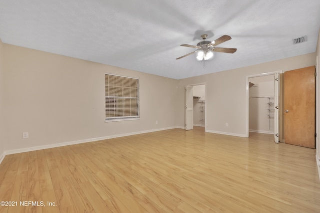 spare room featuring light wood-type flooring, a textured ceiling, and ceiling fan