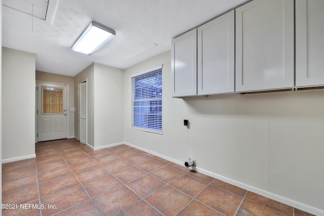 laundry room featuring tile patterned flooring, cabinets, and electric dryer hookup