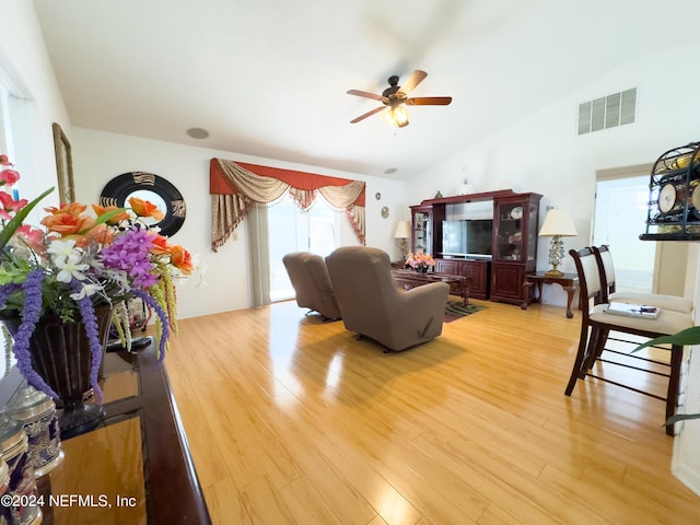 living room featuring vaulted ceiling, light wood-type flooring, visible vents, and ceiling fan