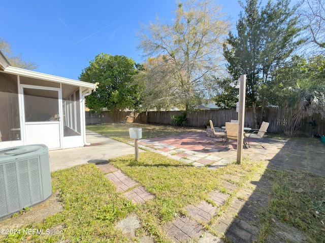 view of yard with a sunroom, a patio, and central air condition unit