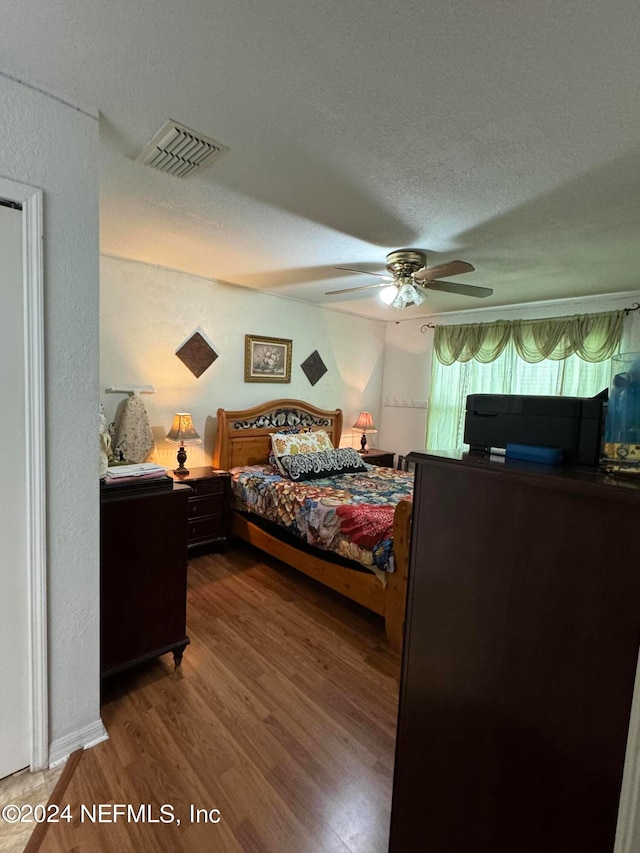 bedroom with ceiling fan, a textured ceiling, and hardwood / wood-style floors