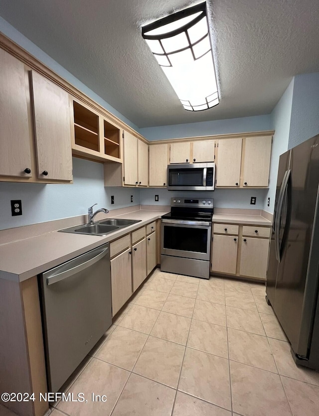 kitchen with a textured ceiling, stainless steel appliances, and light brown cabinets