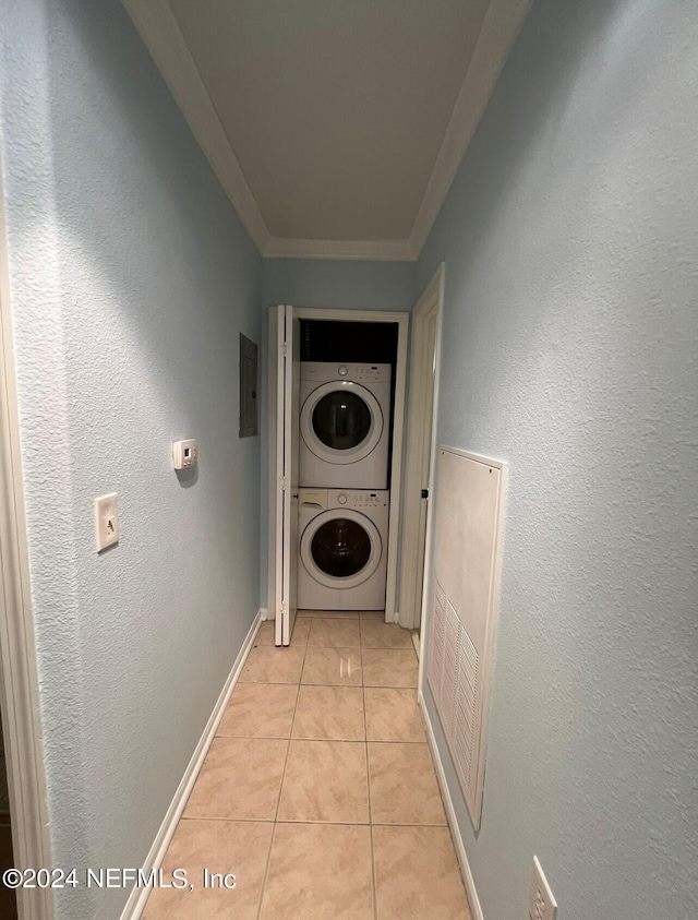 hallway featuring crown molding, stacked washer and clothes dryer, light tile patterned floors, and electric panel