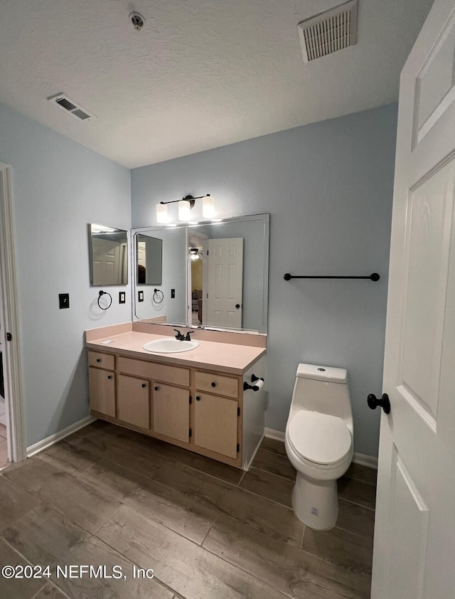 bathroom featuring a textured ceiling, vanity, toilet, and hardwood / wood-style floors