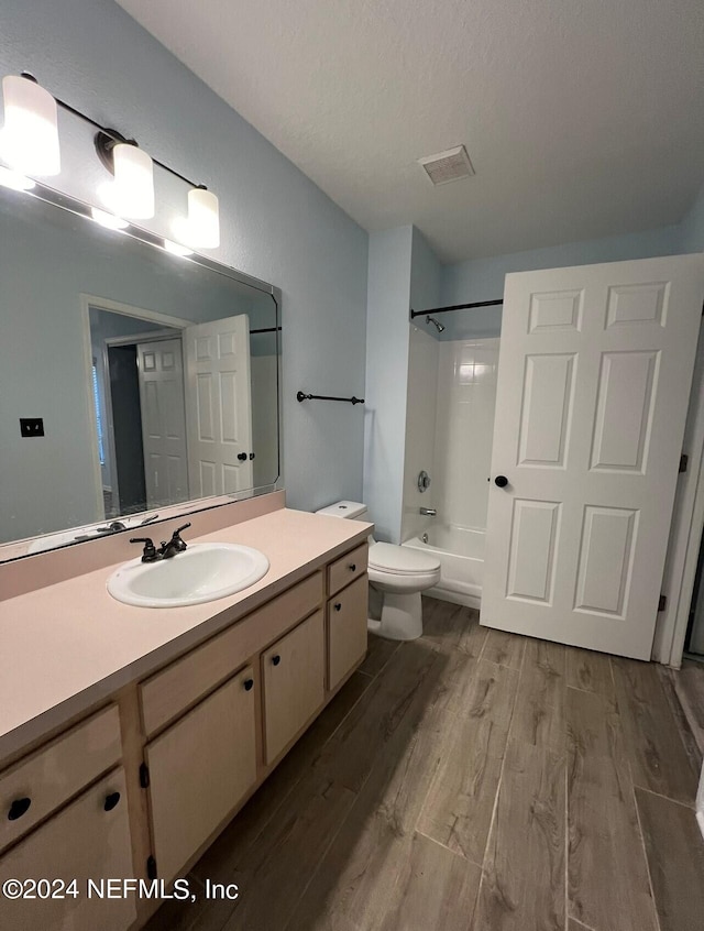 full bathroom featuring toilet, bathing tub / shower combination, wood-type flooring, vanity, and a textured ceiling