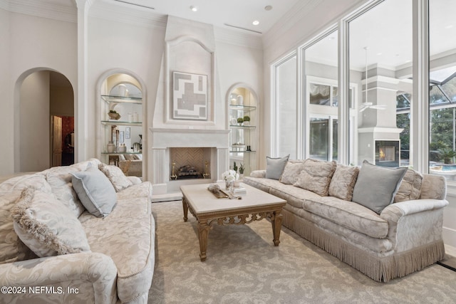 carpeted living room with a large fireplace, crown molding, and built in features