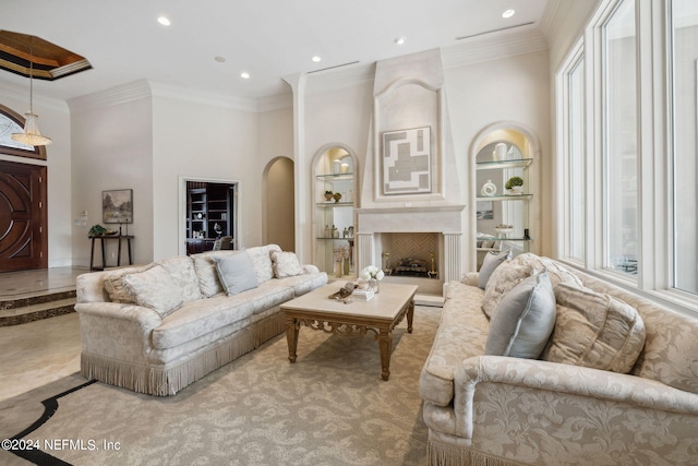 living room featuring ornamental molding, a large fireplace, and built in features