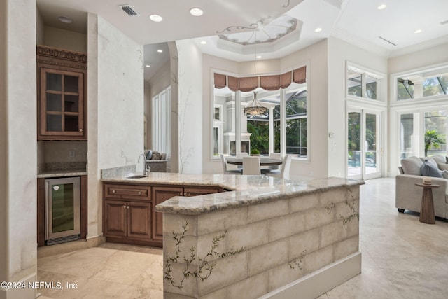 bar featuring wine cooler, ornamental molding, sink, and light stone counters