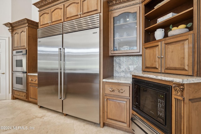 kitchen with built in appliances, light stone counters, and backsplash