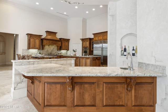 kitchen with kitchen peninsula, crown molding, sink, custom exhaust hood, and appliances with stainless steel finishes