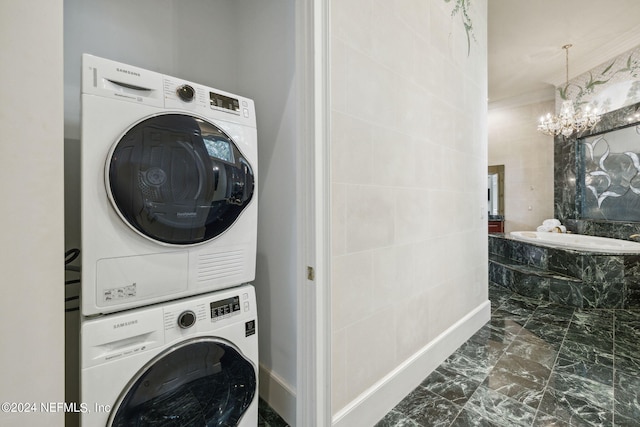 laundry room with a notable chandelier and stacked washer and clothes dryer