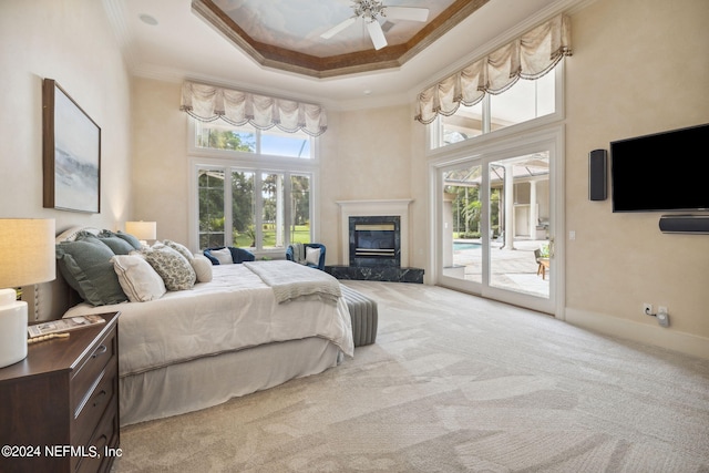 carpeted bedroom with access to outside, ornamental molding, a fireplace, a towering ceiling, and ceiling fan