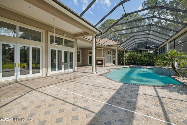 view of pool with a patio, pool water feature, ceiling fan, and glass enclosure