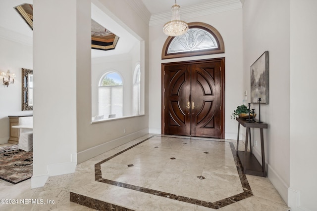 foyer entrance with ornamental molding and an inviting chandelier