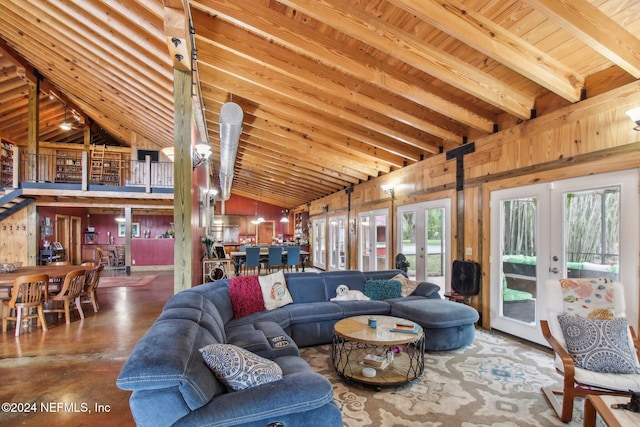 living area featuring vaulted ceiling with beams, concrete flooring, wood walls, wood ceiling, and french doors