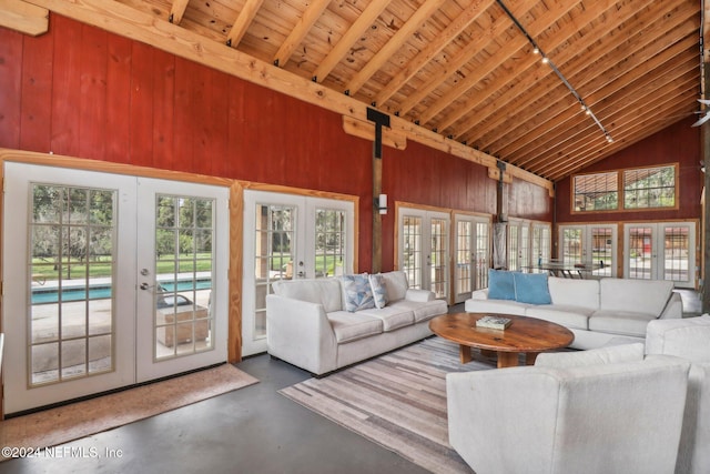 living area featuring high vaulted ceiling, wooden ceiling, concrete floors, wood walls, and french doors