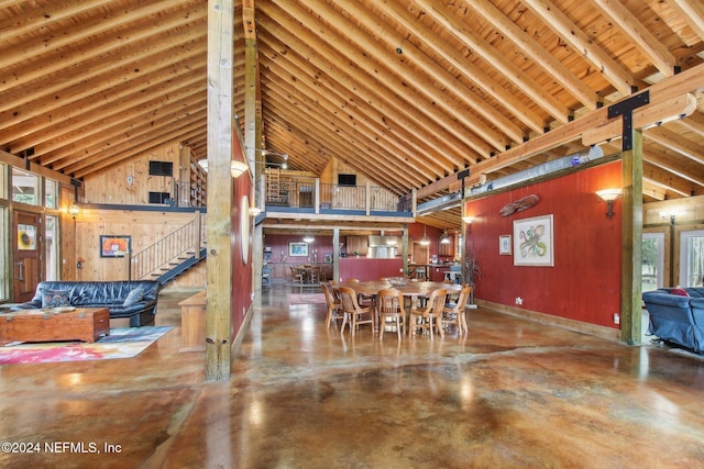 dining space featuring high vaulted ceiling, concrete floors, baseboards, and stairs