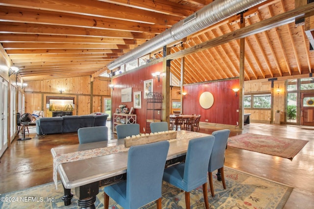 dining room featuring finished concrete flooring, lofted ceiling with beams, and wooden walls