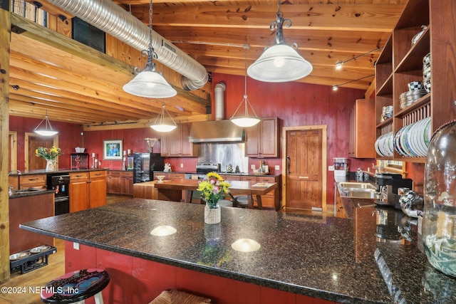 kitchen featuring a kitchen island, freestanding refrigerator, a peninsula, a high ceiling, and wall chimney range hood