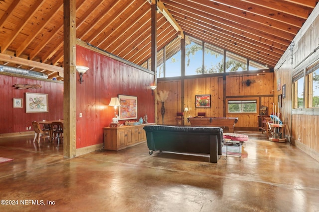 living area featuring wood walls, finished concrete floors, and high vaulted ceiling